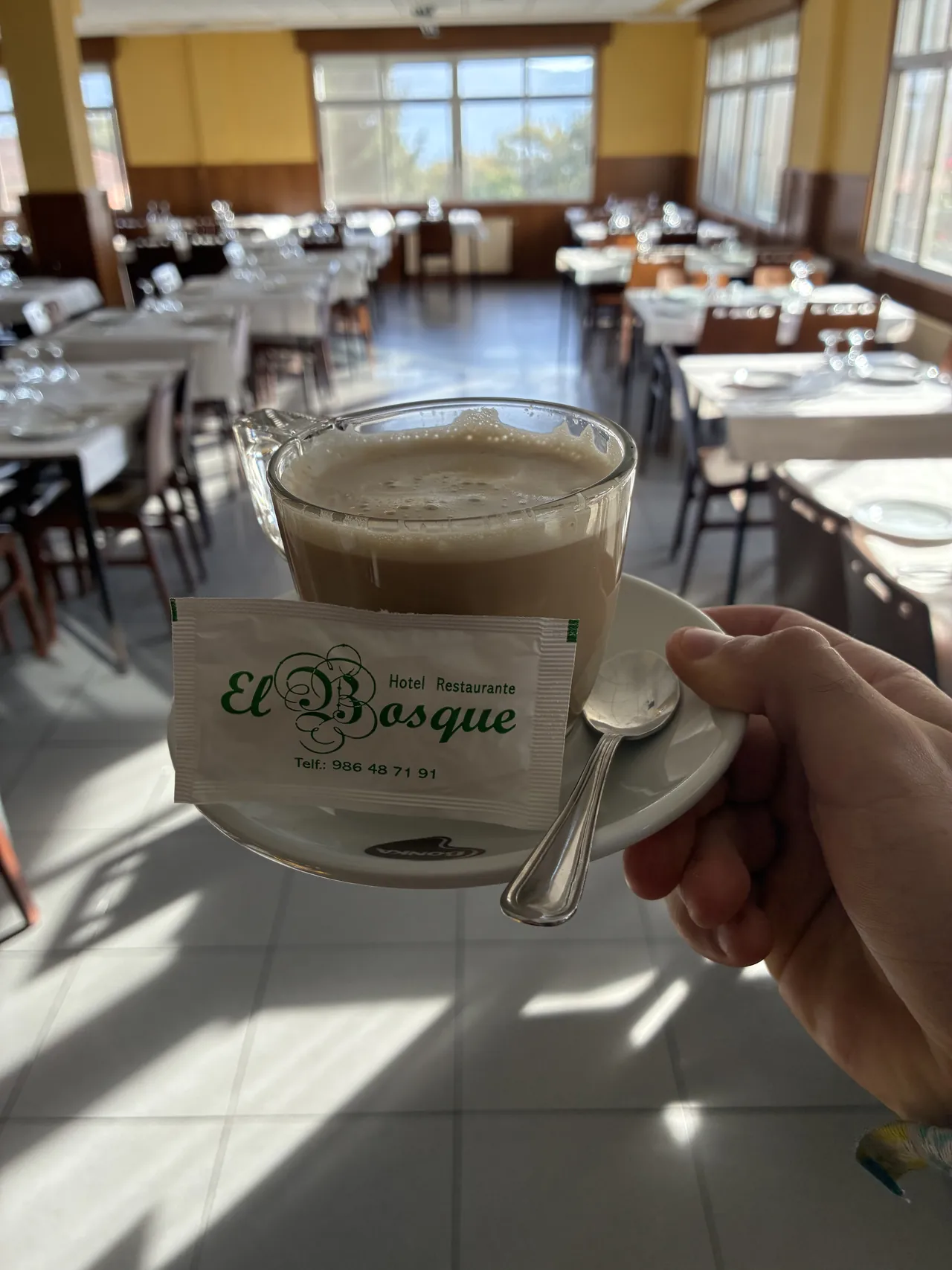 Café servido en una taza de El Bosque con el comedor al fondo
