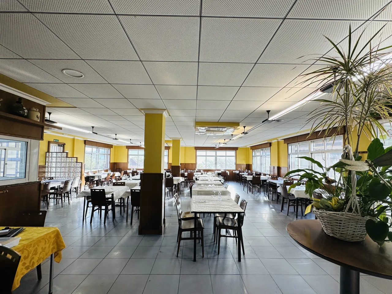 Comedor del restaurante El Bosque en Peinador (Mos), amplio y luminoso, con columnas amarillas y mesas preparadas