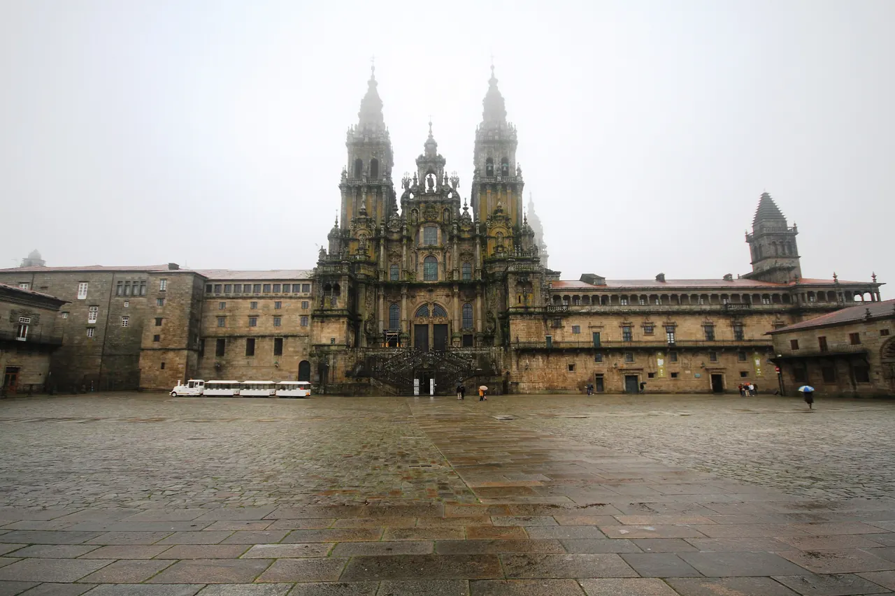 Plaza del Obradoiro mojada por la lluvia, con la catedral de Santiago al fondo entre la niebla