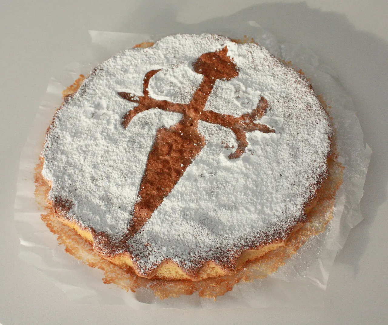 Tarta de Santiago entera, cubierta de azúcar glas con la silueta de la cruz de Santiago