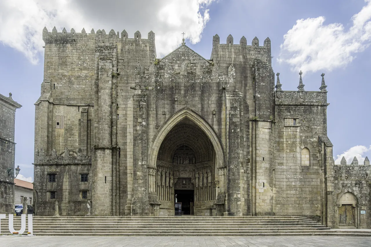 Fachada de la catedral de Tui, de piedra y con almenas, con su gran portada gótica y la escalinata delante