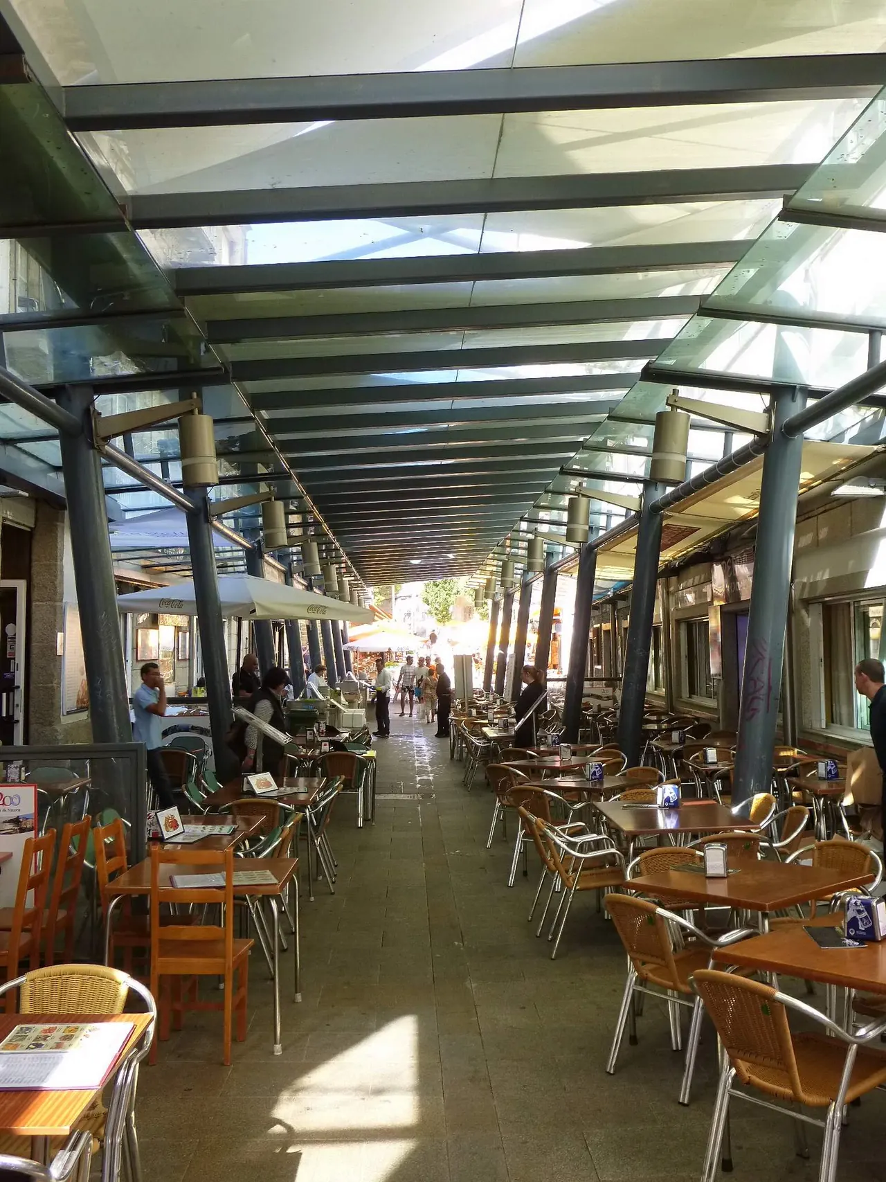 Calle de las ostras de Vigo: un pasaje cubierto con techo de cristal y mesas de terraza a ambos lados