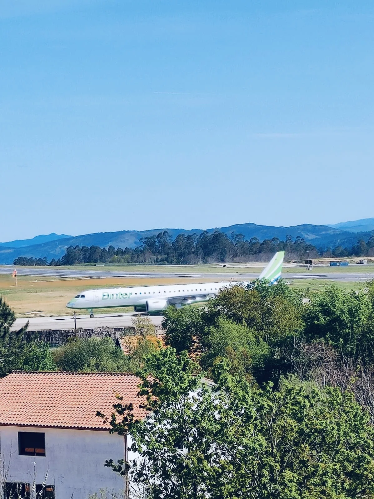 Avión y pista vistos entre los edificios y el paisaje desde El Bosque