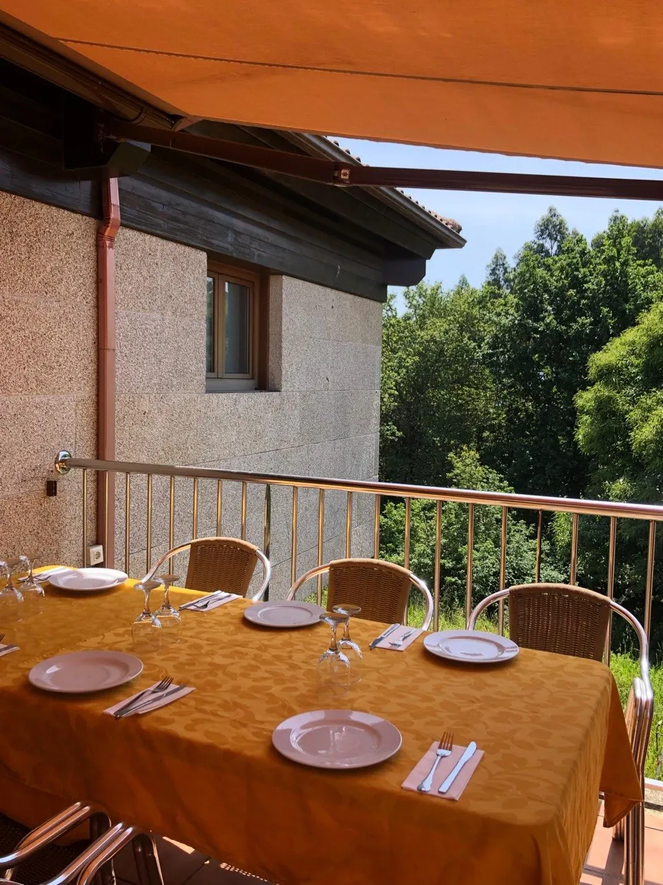 Mesa larga preparada en la terraza de El Bosque, en Mos, con el bosque al fondo
