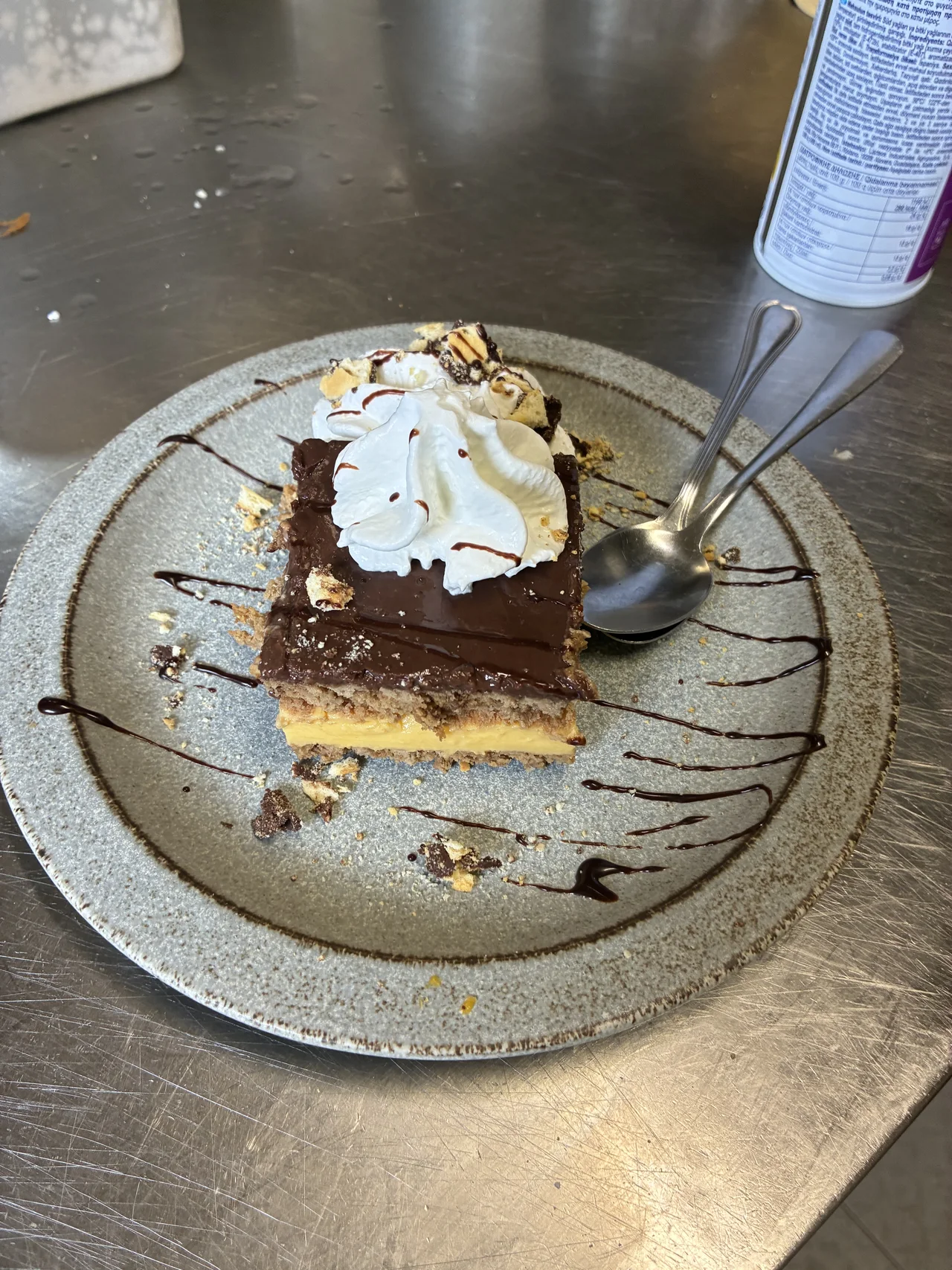 Porción de tarta con cobertura oscura y nata sobre un plato