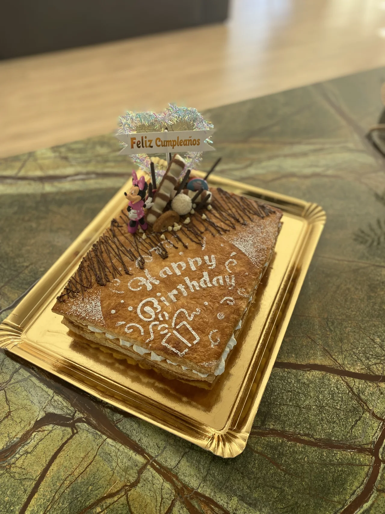 Tarta rectangular con un mensaje de cumpleaños sobre una bandeja dorada