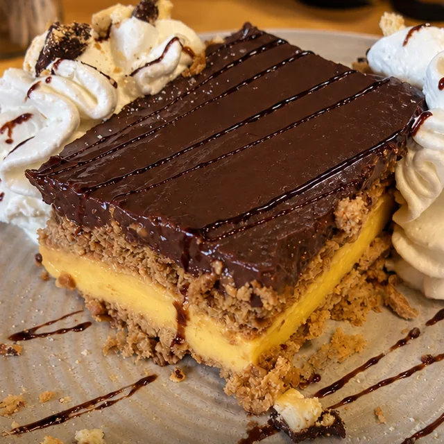 Tarta de galleta, crema y chocolate con nata, postre de la casa en El Bosque